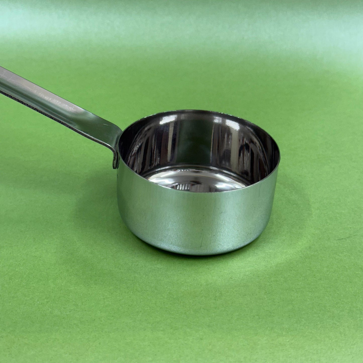 Stainless steel batter serving ladle shown at an angle with deep bowl