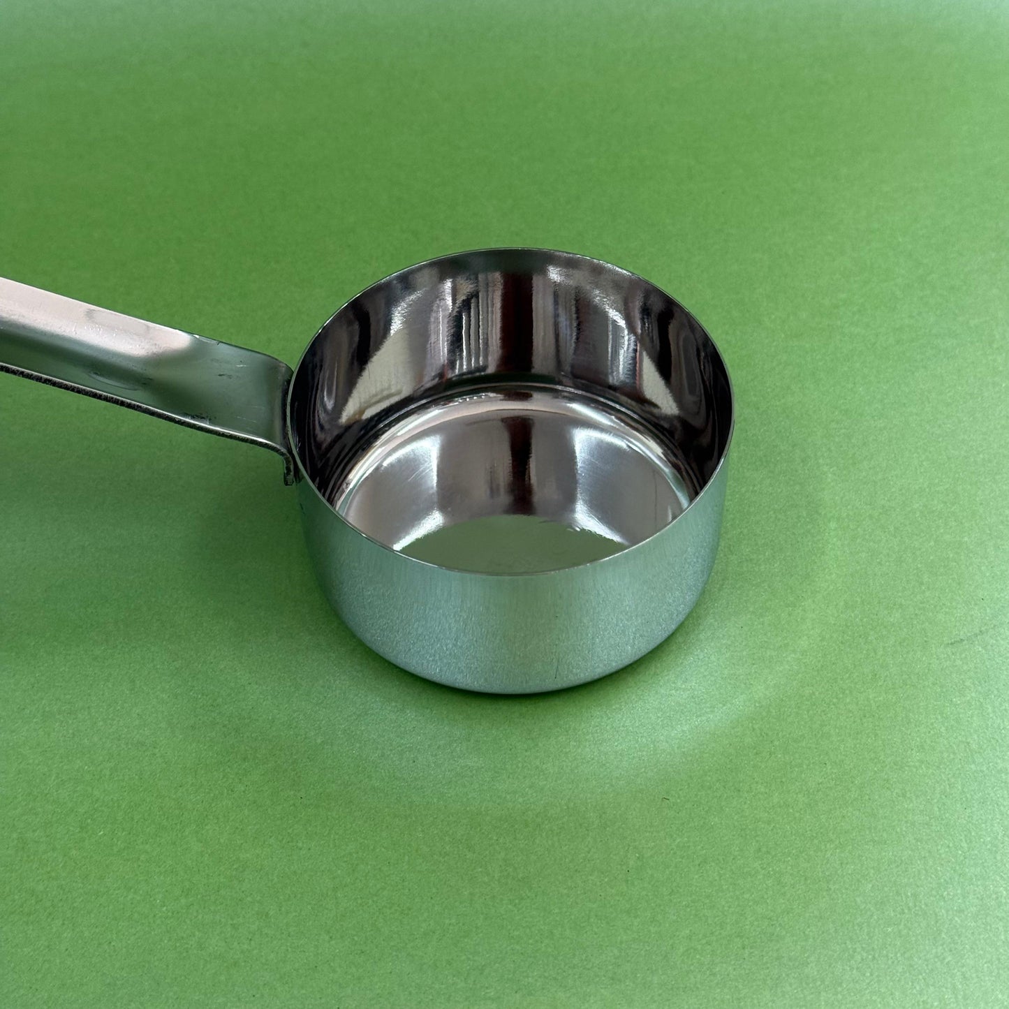 Stainless steel batter serving ladle shown at an angle with deep bowl