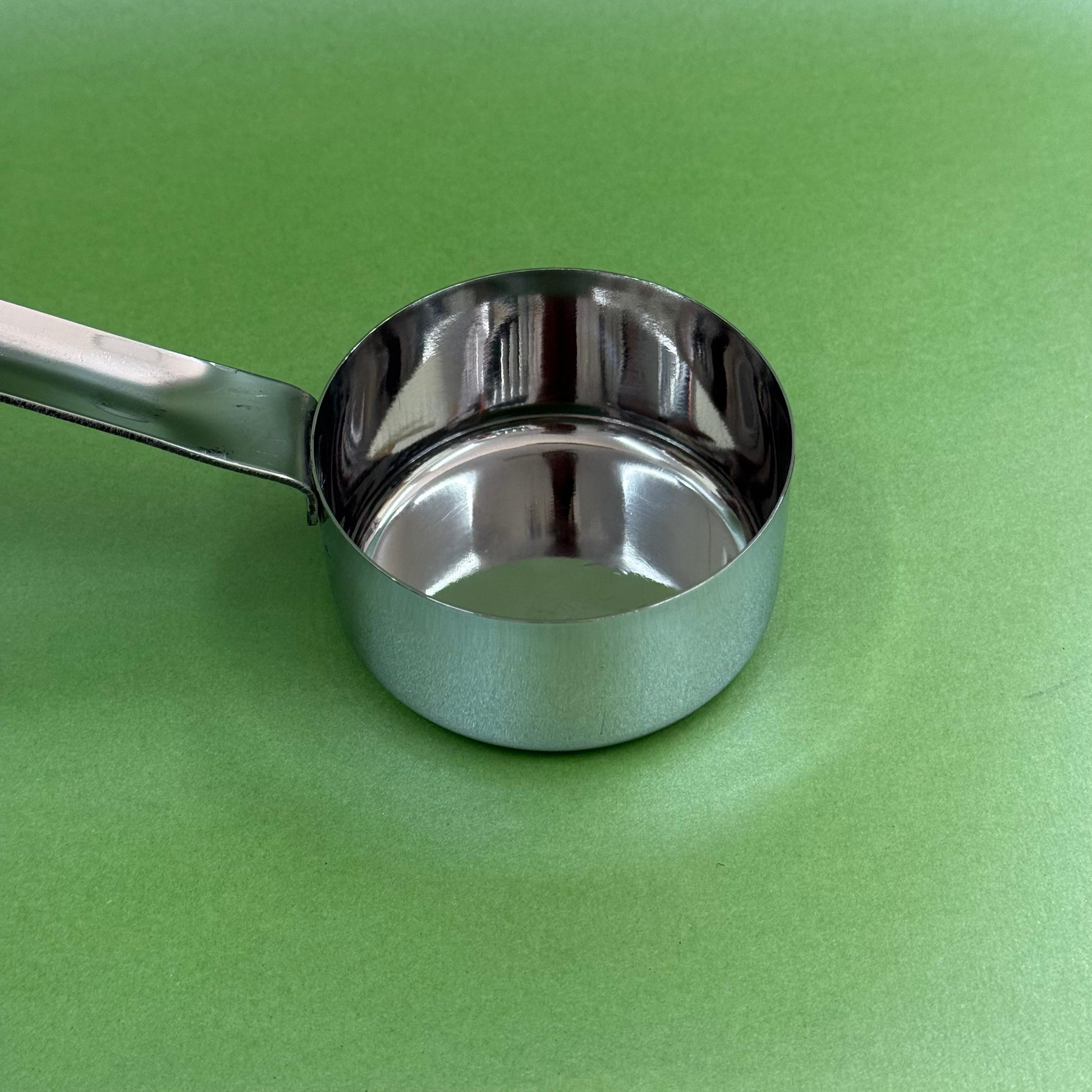 Stainless steel batter serving ladle shown at an angle with deep bowl