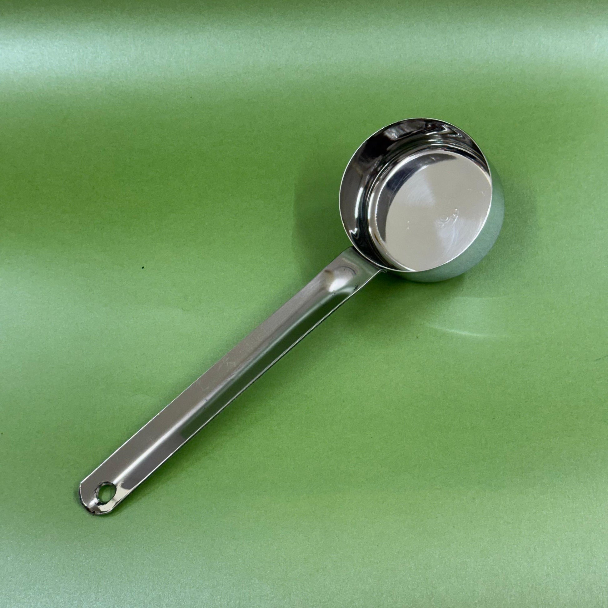 Stainless steel batter serving ladle highlighting the long handle grip