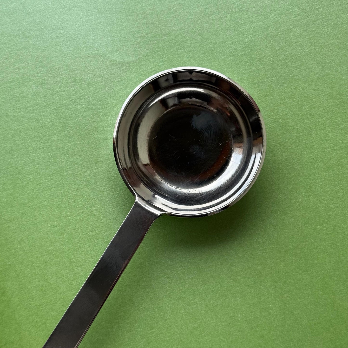 Stainless steel dosa batter ladle being used to pour dosa batter on a tawa
