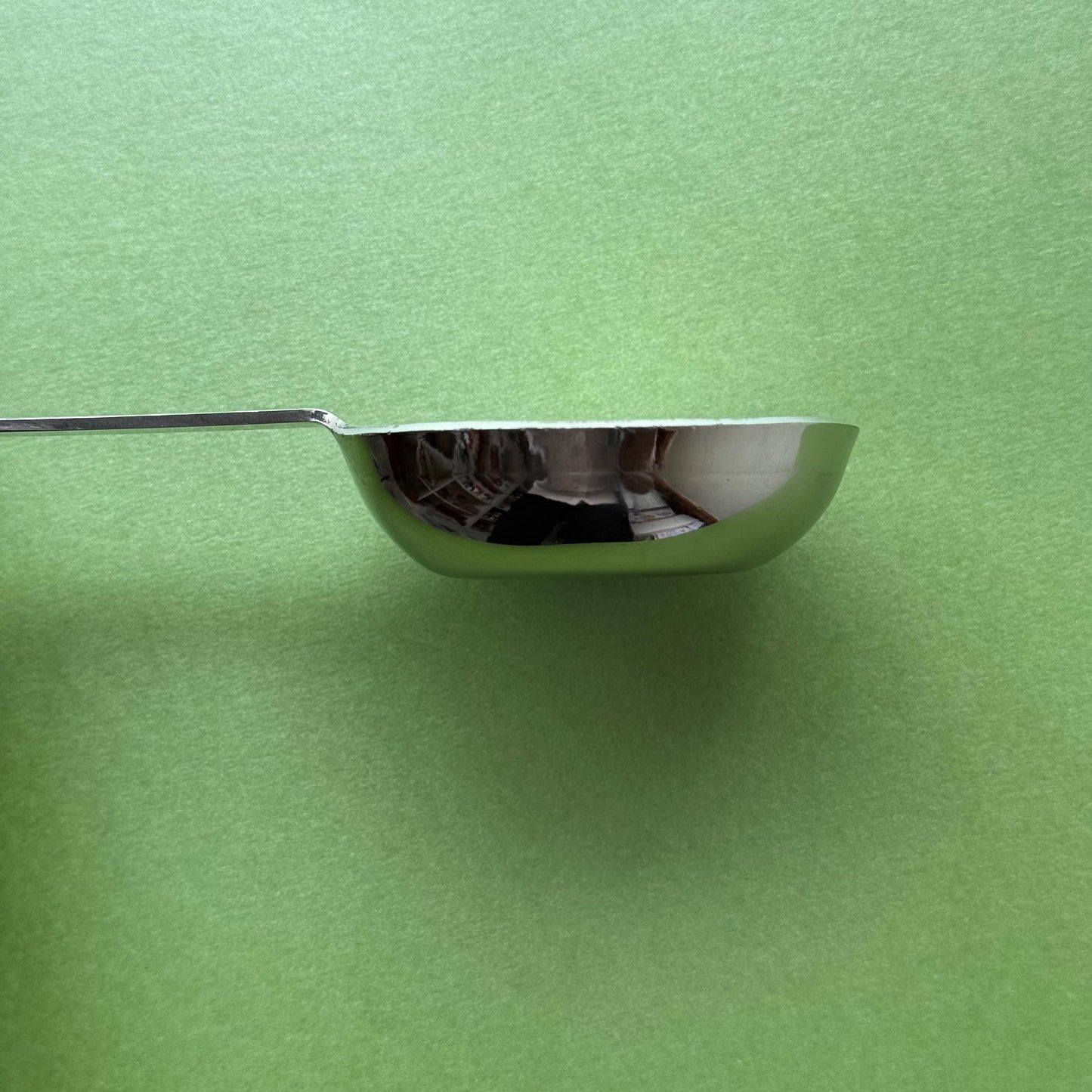 Stainless steel dosa batter ladle being used to pour dosa batter on a tawa