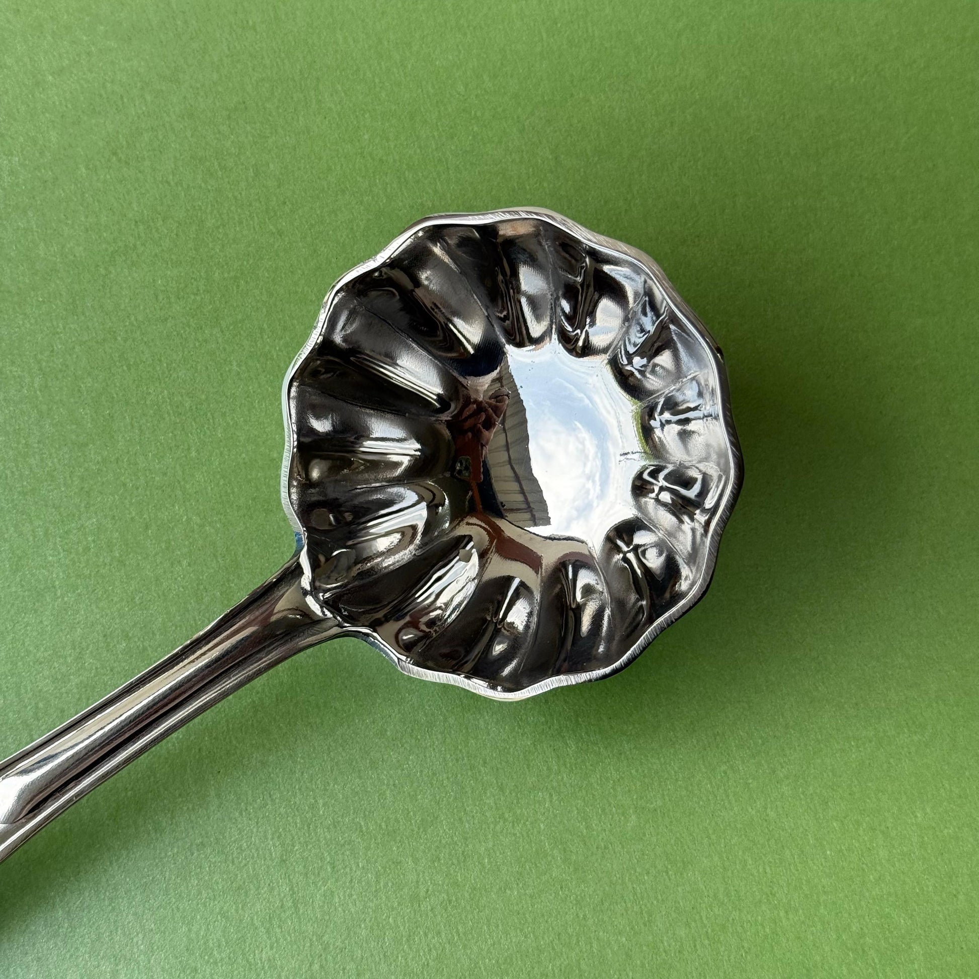 Side view of stainless steel flower ladle highlighting flower design bowl