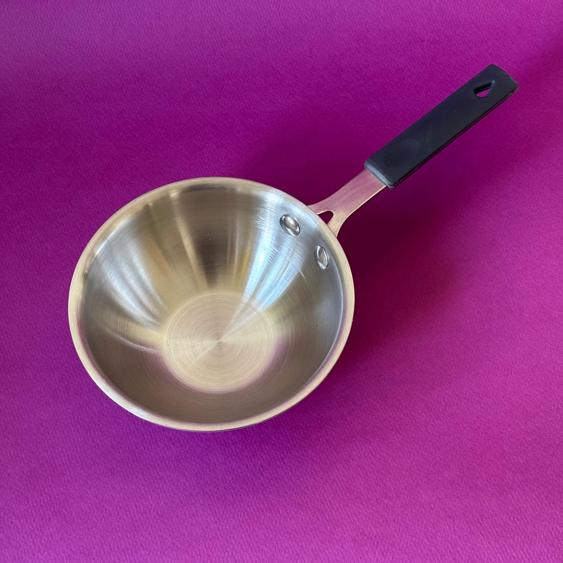 Triply stainless steel wok pan bottom showing triply construction and induction compatibility icons